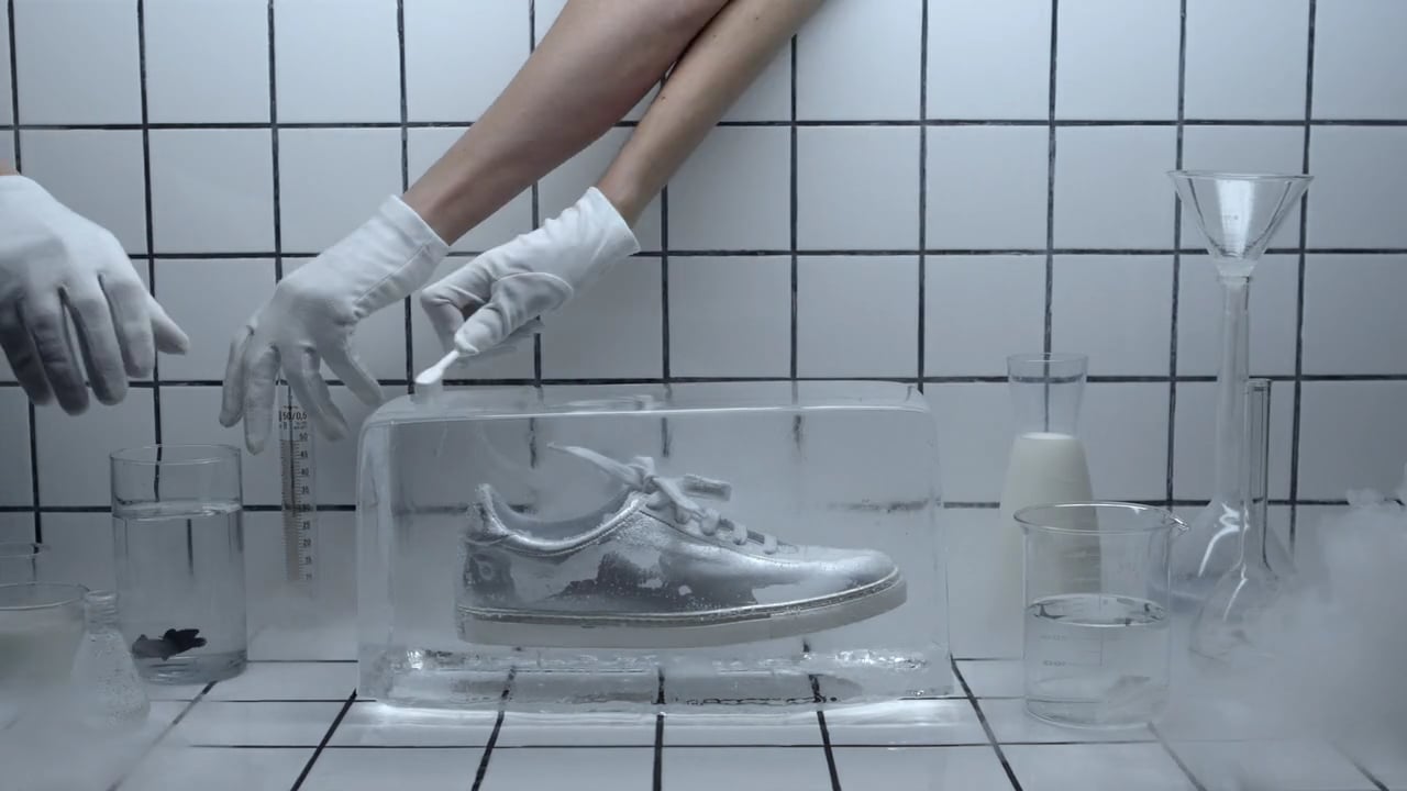 A metallic sneaker in a laboratory display, from the original brand film.